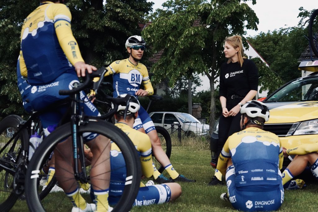 Rennradsportler und Trainerin im Kreis, Vorbesprechung