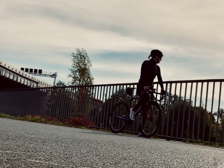 Rennradfahrerin an einem Gelände mit Blick weggerichtet , sepia eingefärbt